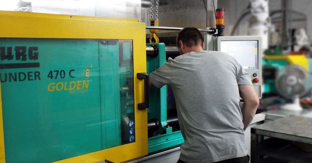 Man operating injection moulding machine